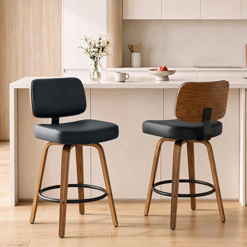 Pair of black padded bar stools with curved backs, swivel seats, light wood legs, footrest ring