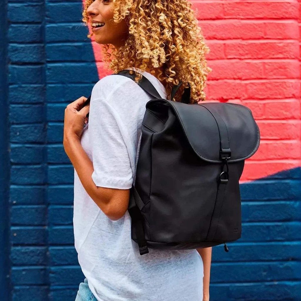 Black changing backpack worn on shoulders, front flap pocket and hanging strap