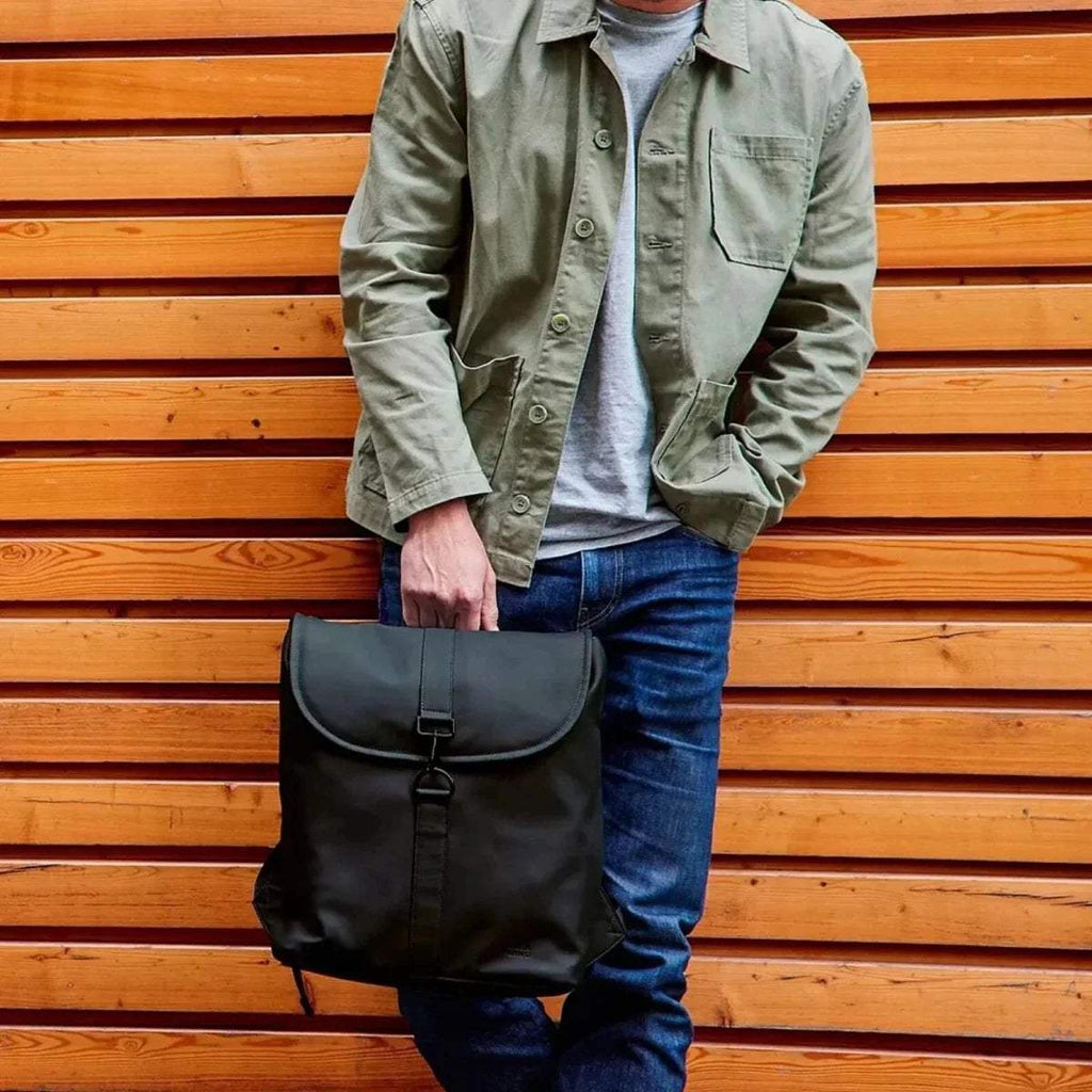 Black changing backpack held in front with front flap, shoulder straps, and buckles