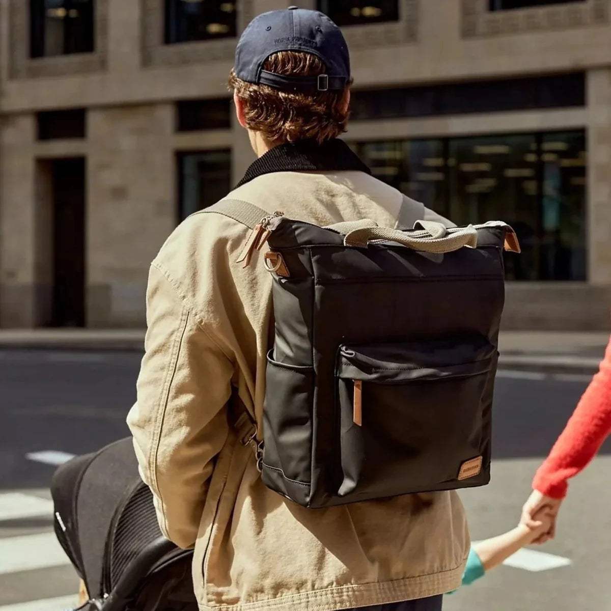 Black changing backpack worn on back with multiple straps and side zipper pocket