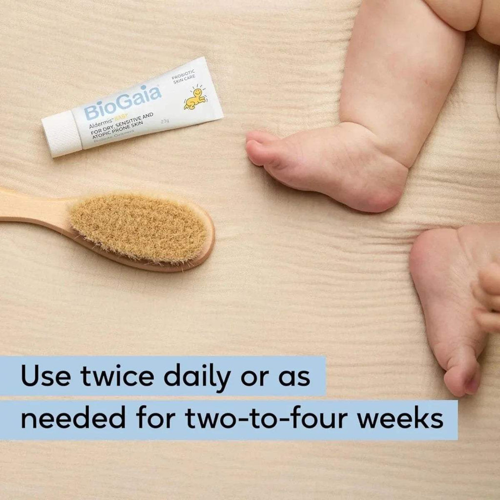 Baby feet with ointment tube and applicator brush on light surface
