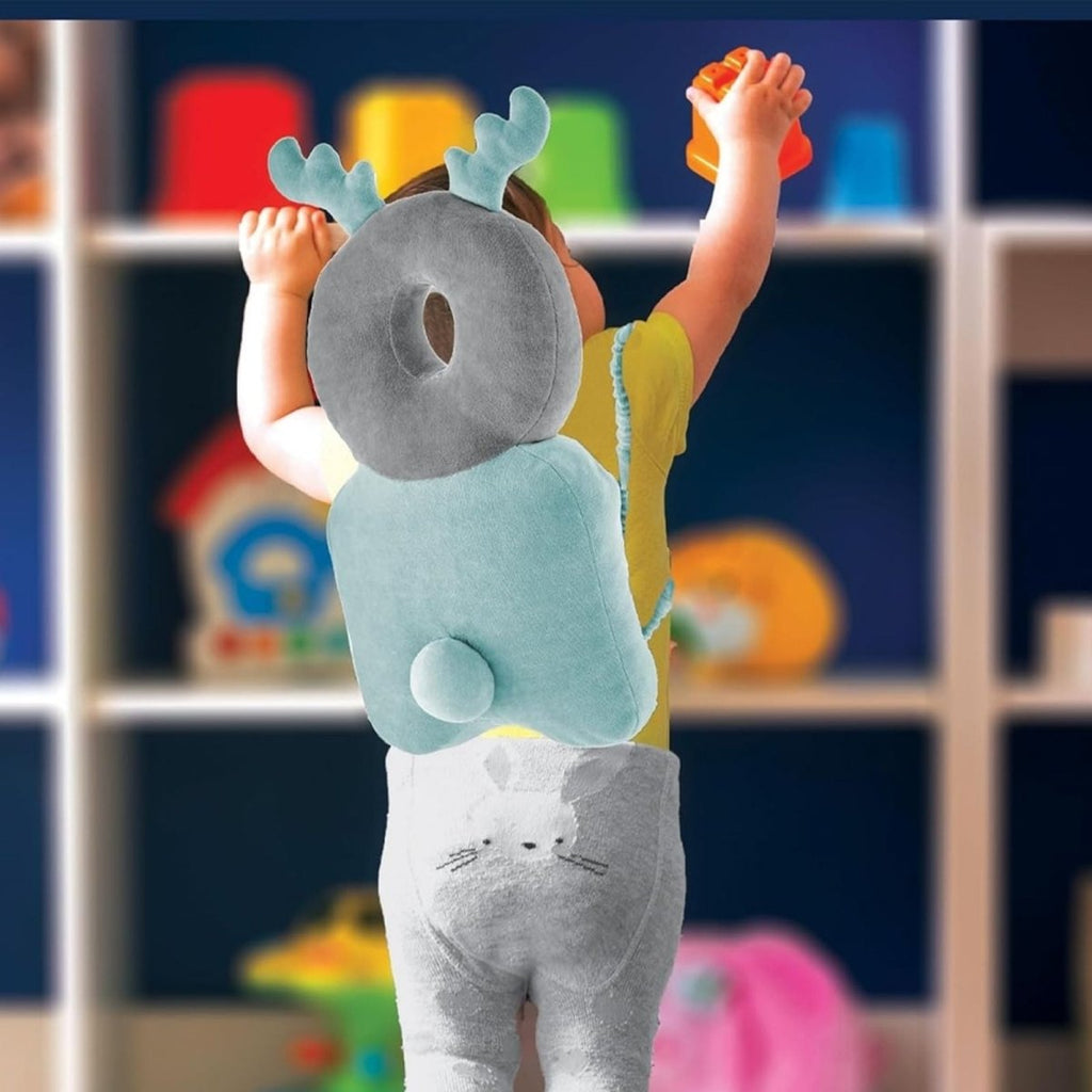 Toddler wearing mint green and gray plush head protector with wing-like ears