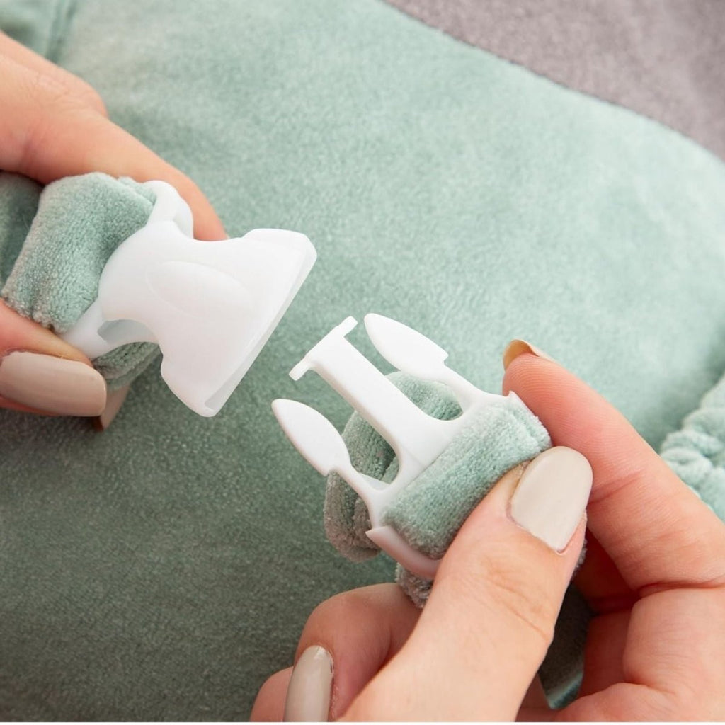 Plush baby head protector close-up: gray donut ring, mint green straps and fasteners