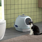 Blue enclosed cat litter box with circular entry, cat sitting beside the doorway
