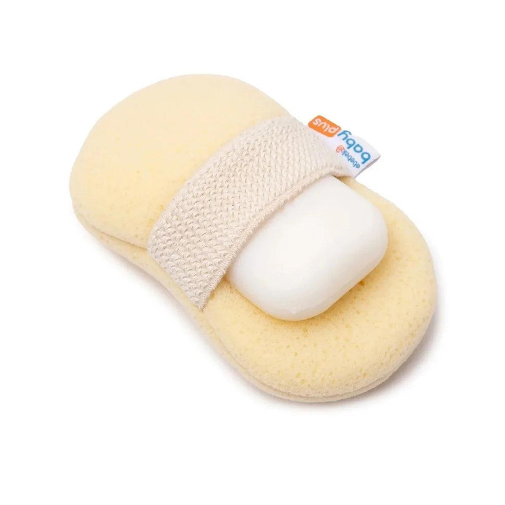 Light beige bath sponge with white soap bar tucked inside, blue care label