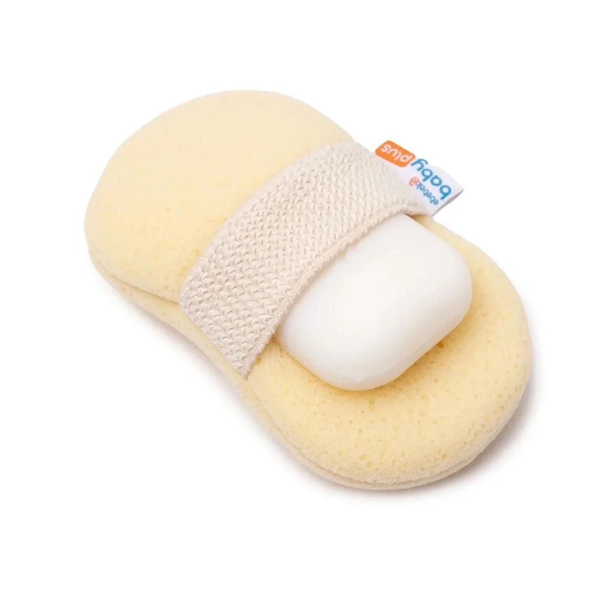 Light beige bath sponge with white soap bar tucked inside, blue care label