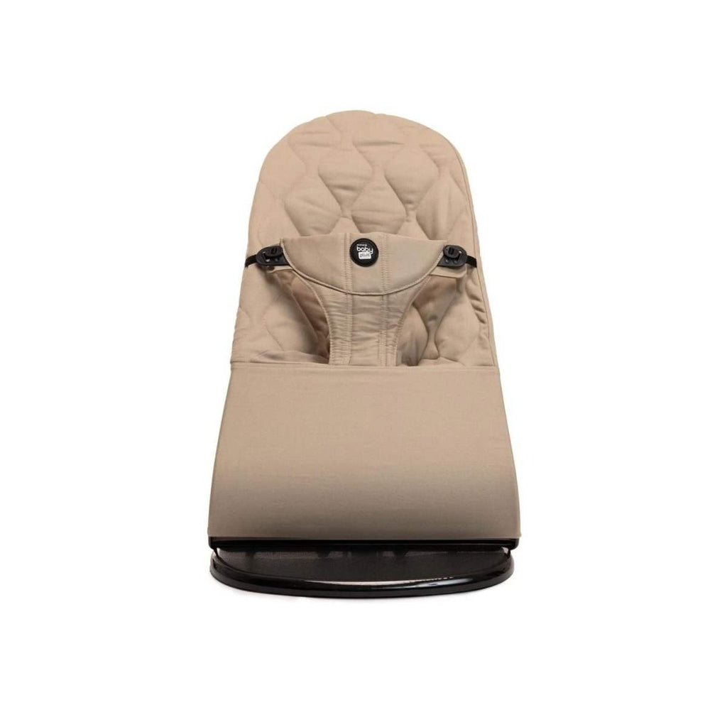 Beige baby bouncer with padded headrest and front harness straps, black base