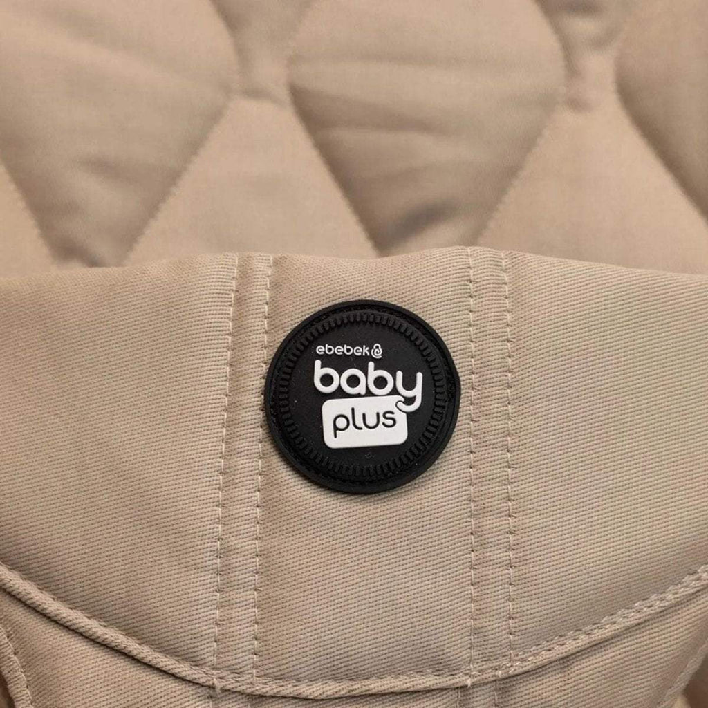 Beige bouncer seat with black "baby plus" logo patch on fabric