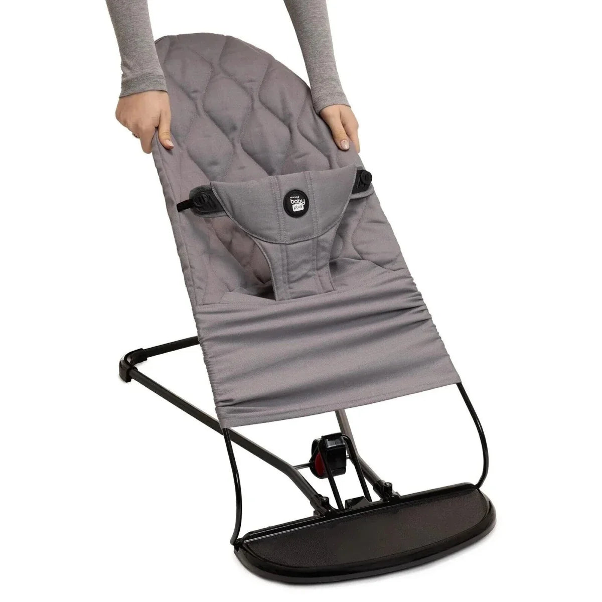 Grey baby bouncer shown being held, with harness and quilted seat
