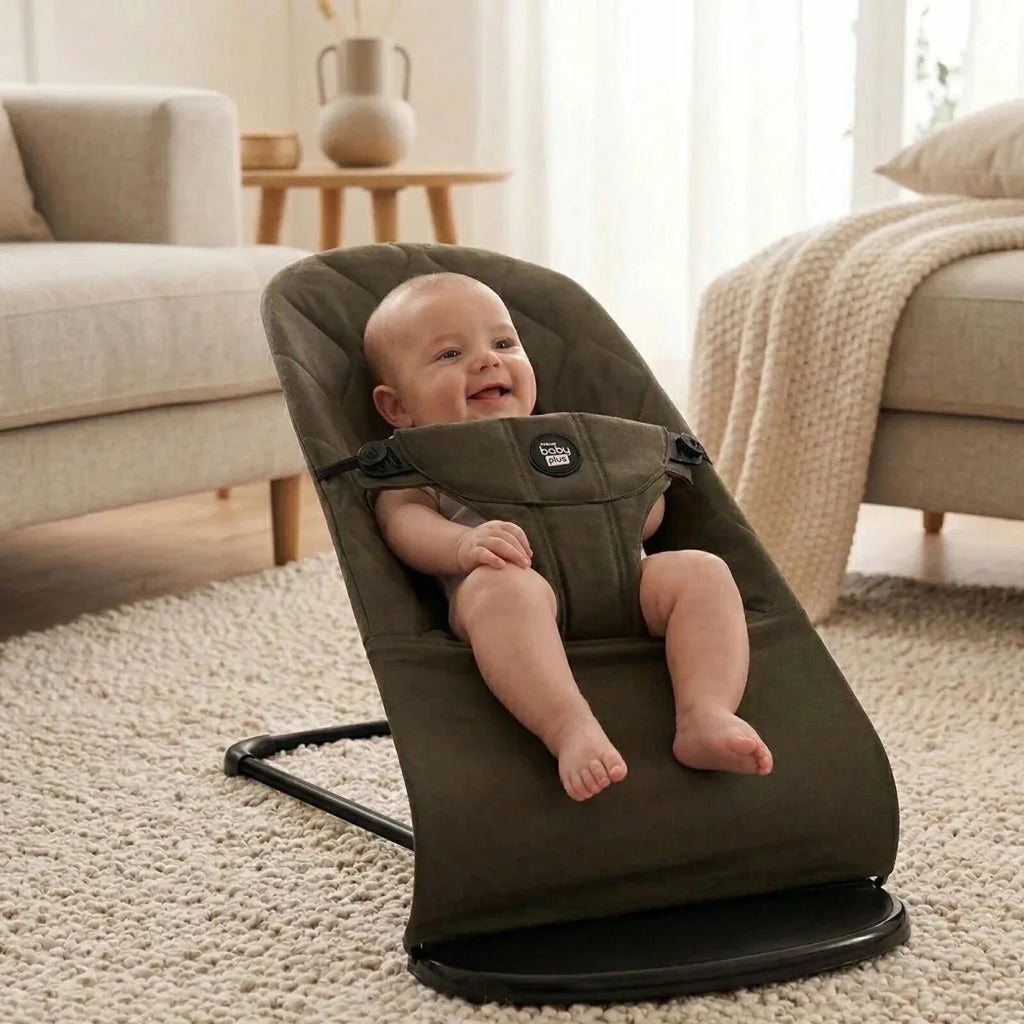 Grey baby bouncer with a baby seated in the quilted fabric seat