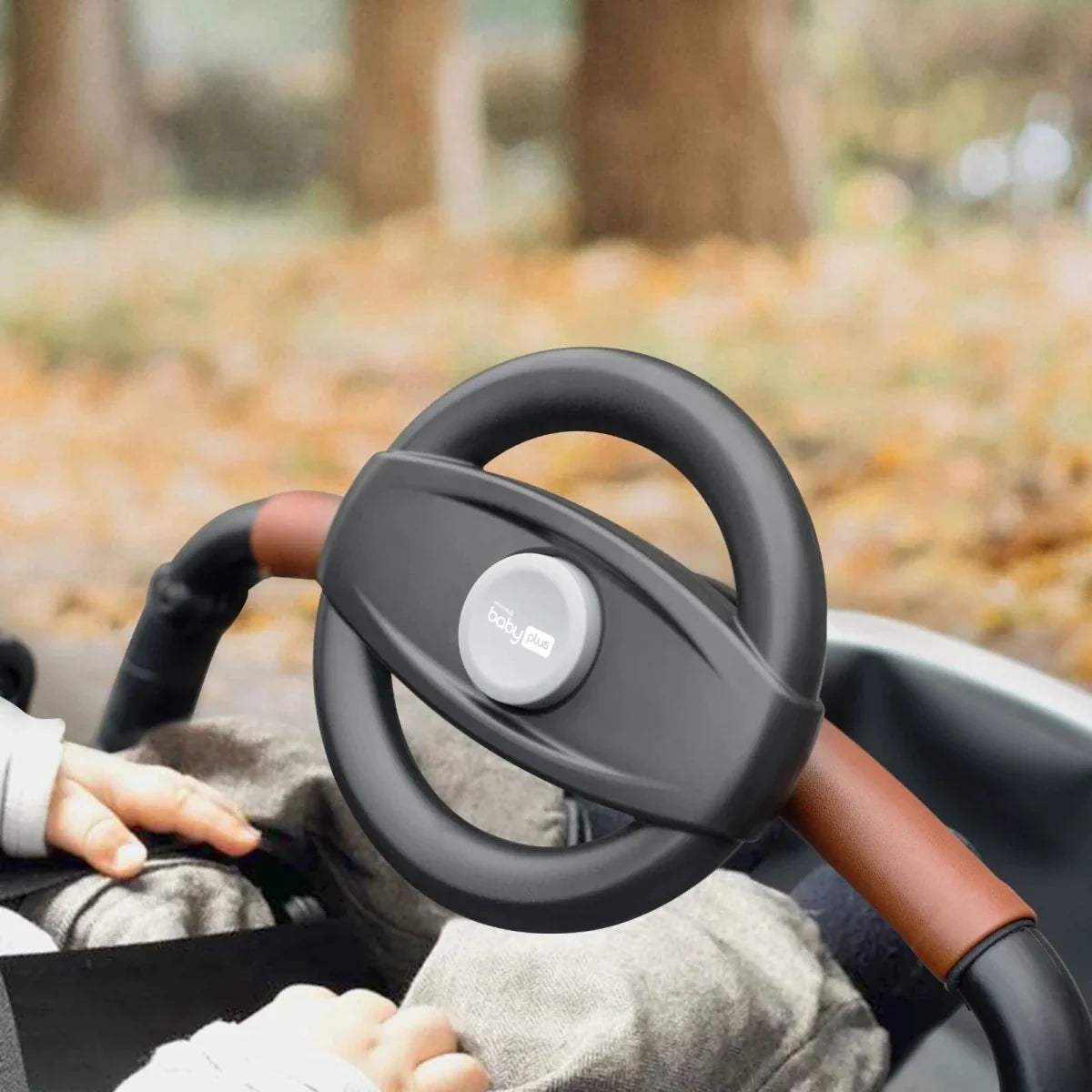 Stroller steering wheel attachment with dark gray rim and central control button, on stroller