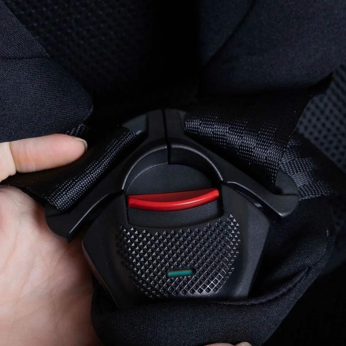 Black car seat belt buckle area with red release button and textured pad
