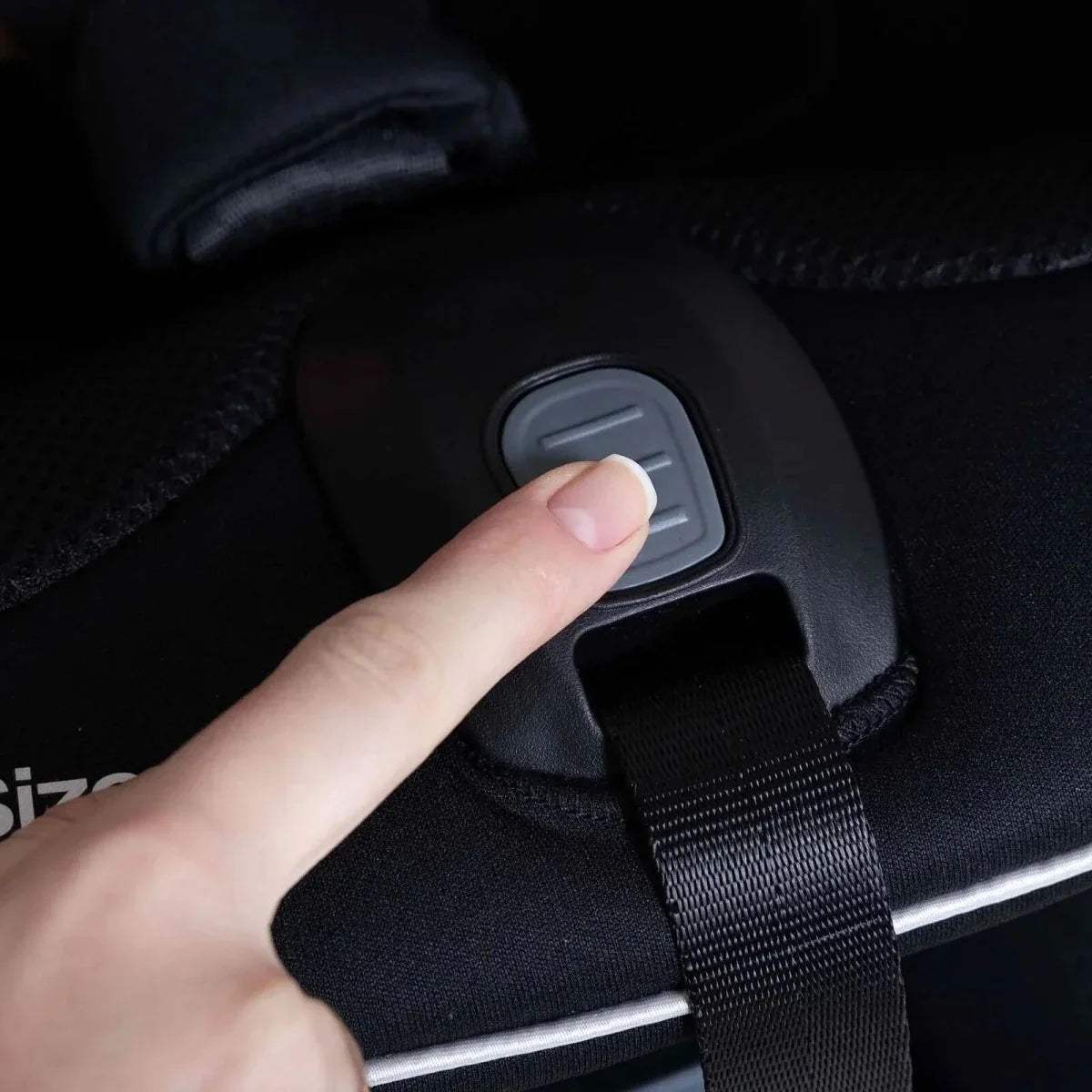 Black car seat chest strap with grey release button and adjustable webbing