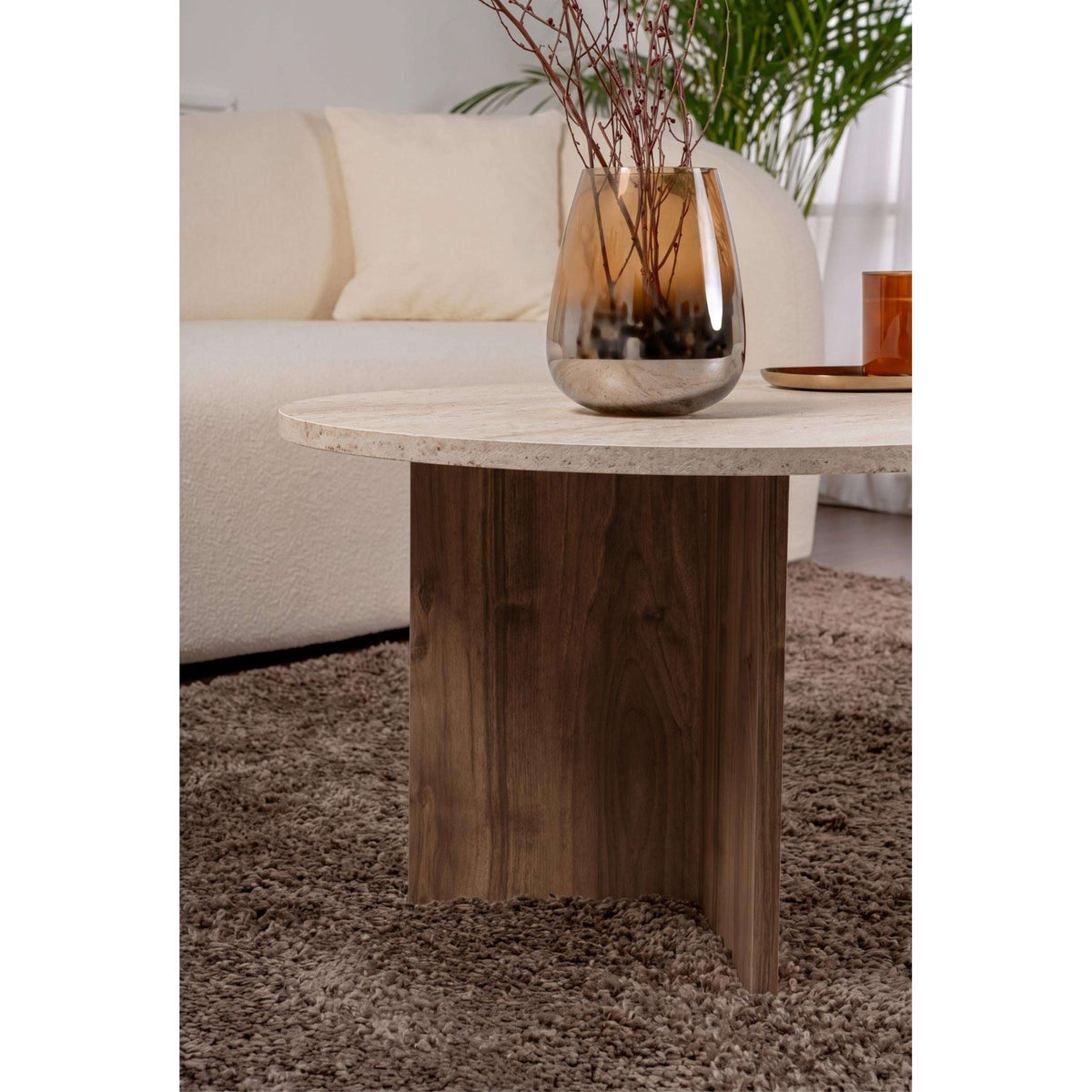 Oval coffee table with light stone top and dark wood cabinet-style base legs