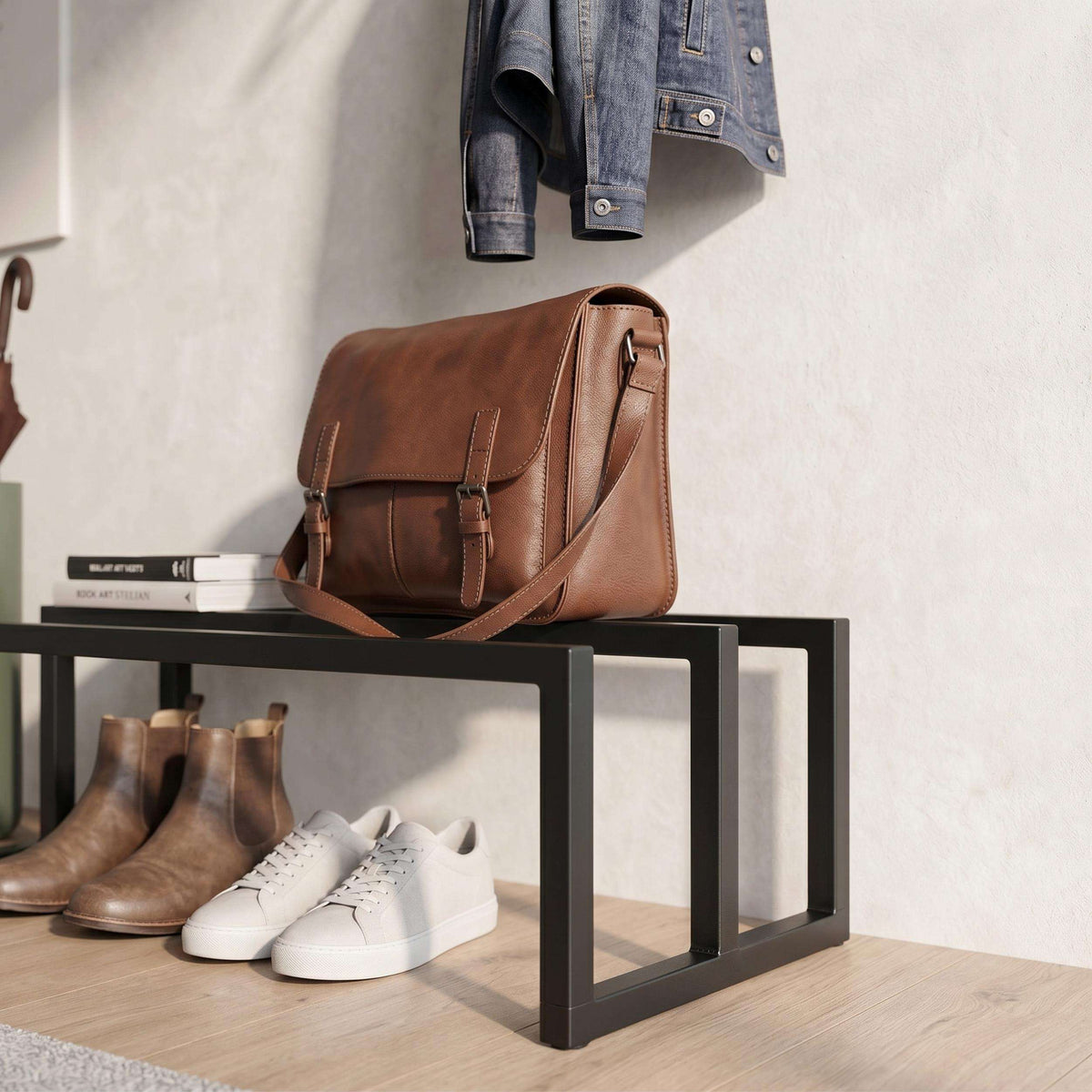Black shoe rack shelf holding brown leather bag, boots, and white sneakers
