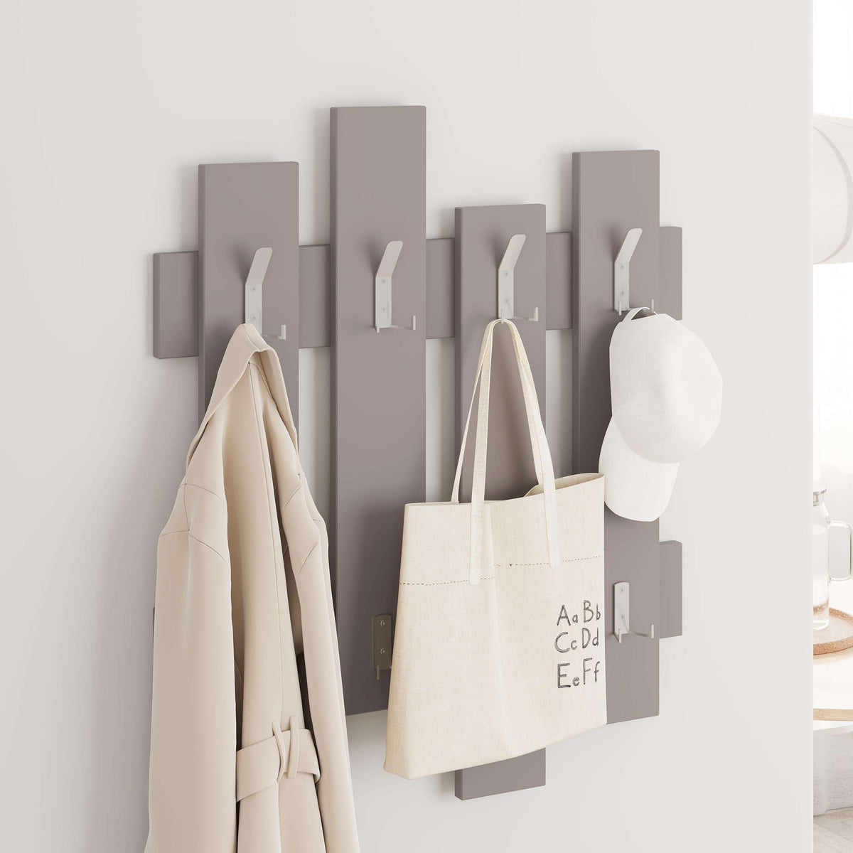 Light taupe wave wall coat rack with hooks, holding tote bag, coat, and cap