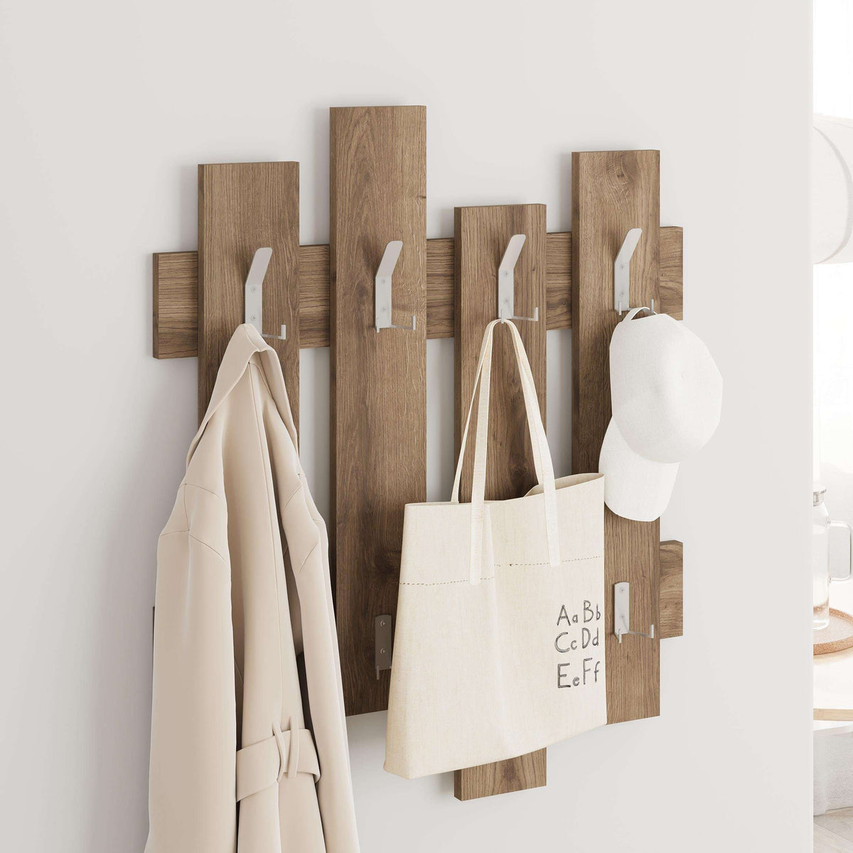 Wood wave coat rack with metal hooks holding tote bag, cap, and coats