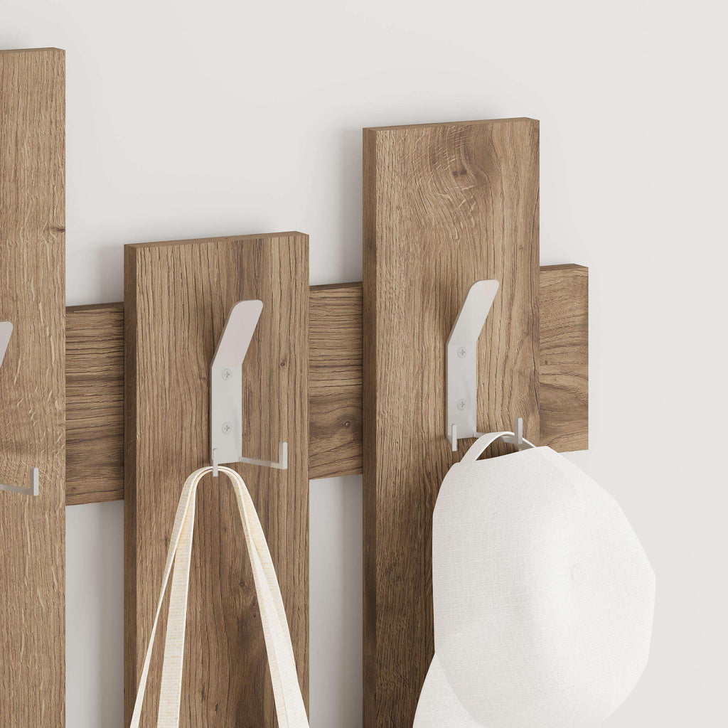 Wood wave coat rack with metal hooks holding a white bag and hat