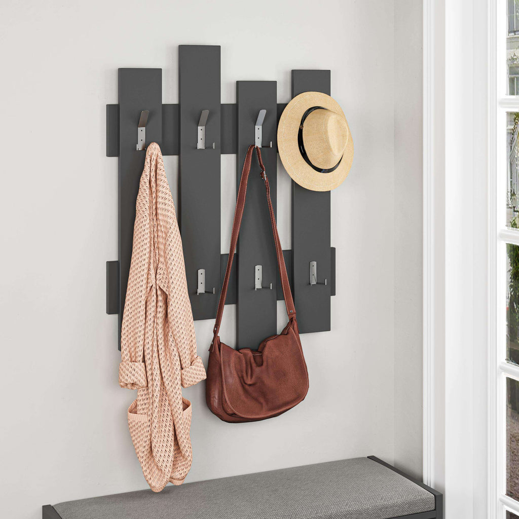 Dark gray coat rack with wave panel hooks, holding a coat, bags, and hat