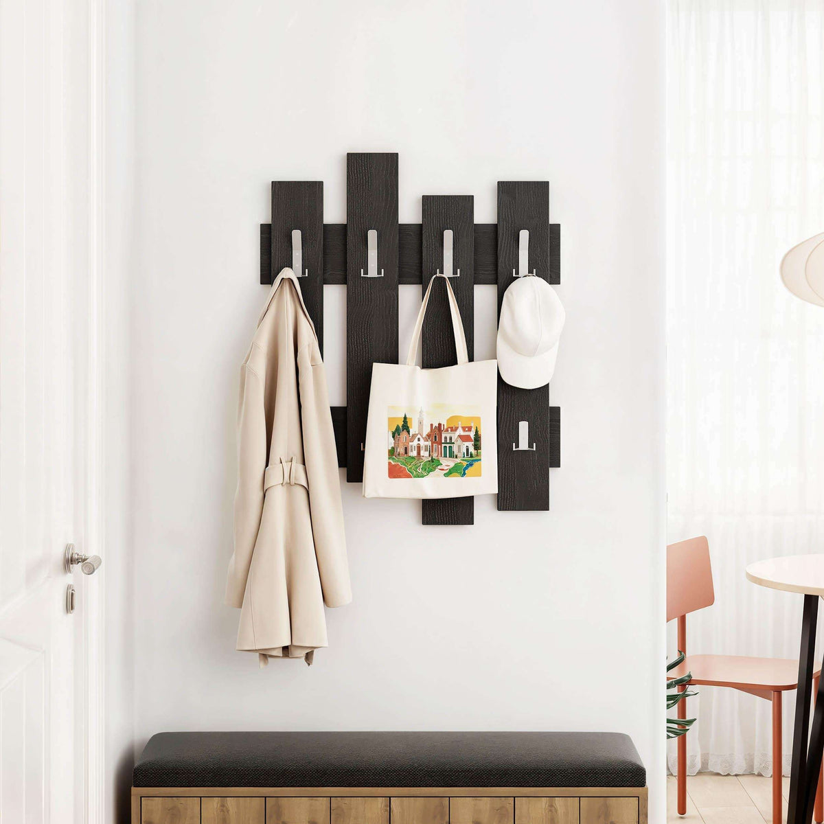 Dark wood coat rack with staggered panels and hooks holding coats and a bag