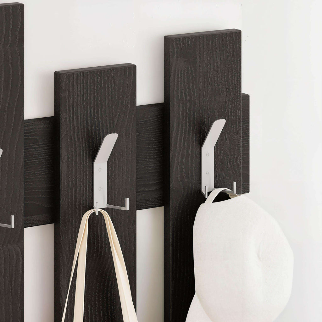 Dark wood coat rack with vertical panel hooks holding a light cloth item