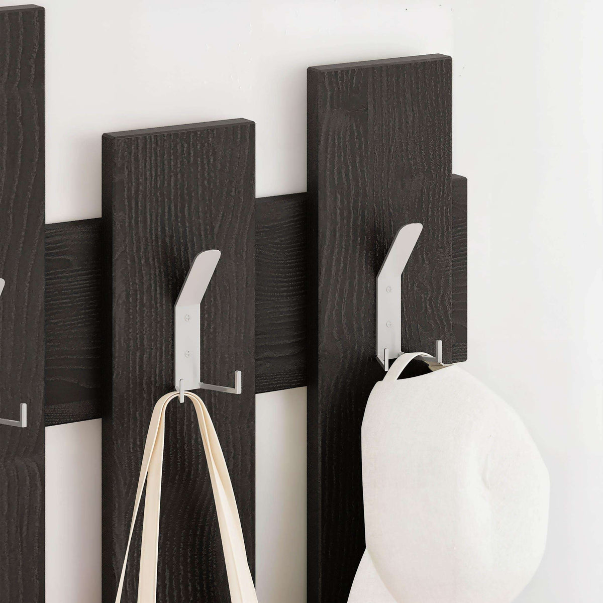 Dark wood coat rack with vertical panel hooks holding a light cloth item
