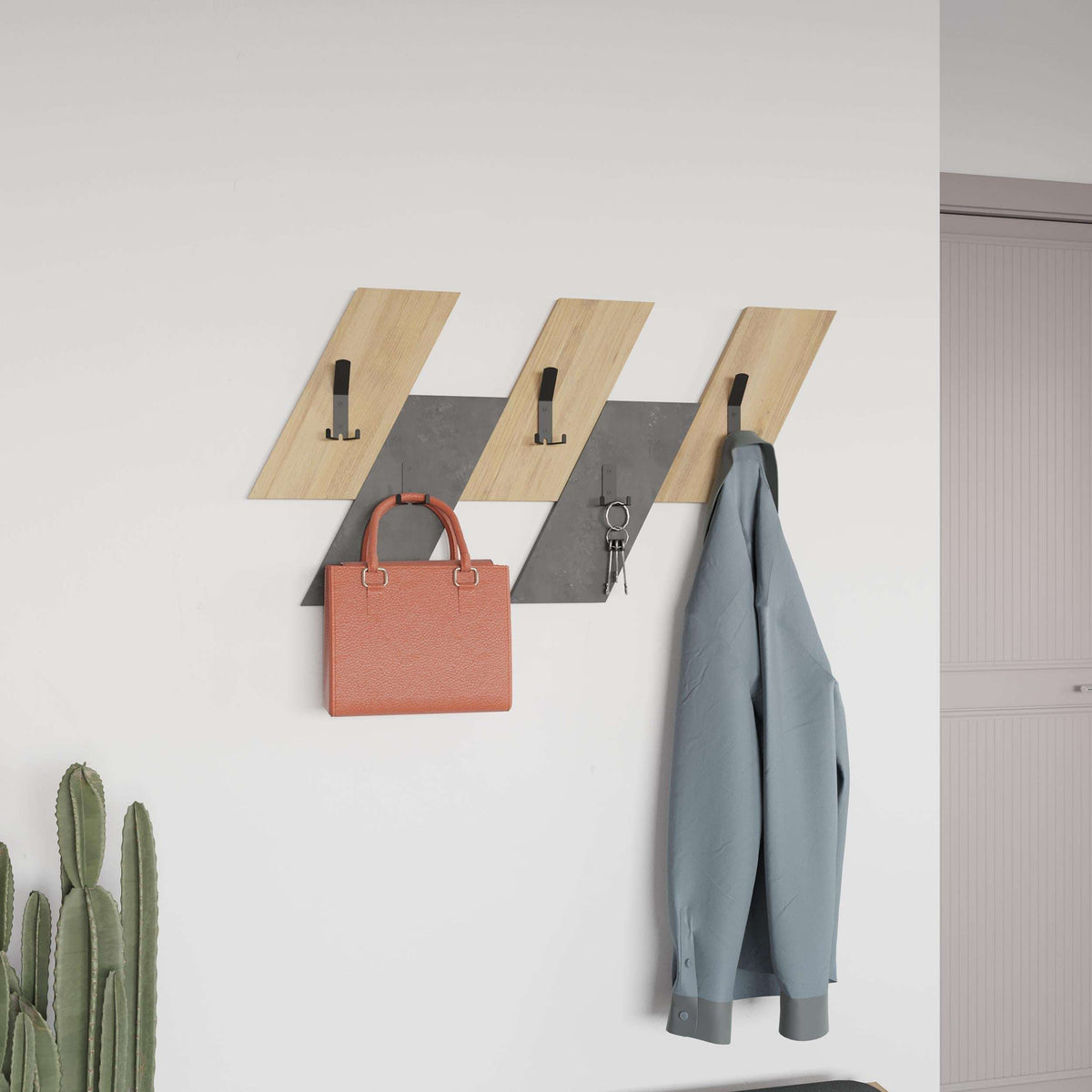 Wall-mounted coat hanger with light oak slats, black hooks, and coat and bag hanging