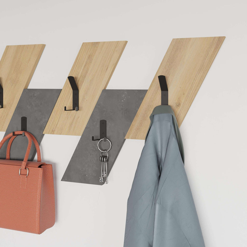 Wall-mounted coat hanger with light oak slats and black hooks holding coats and keys