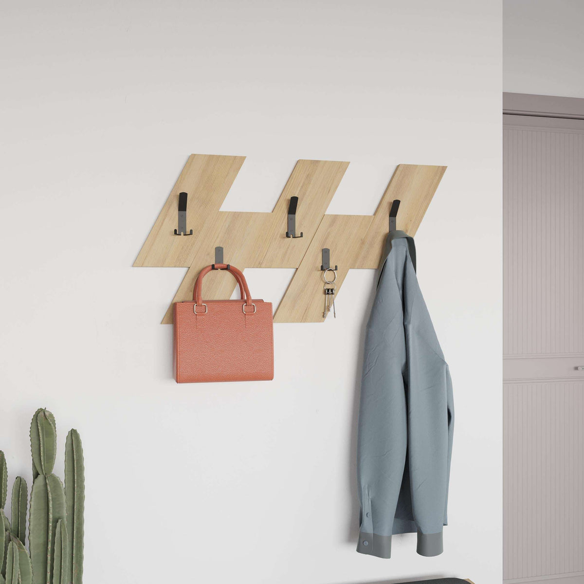Wall-mounted coat hanger set with light wood panels and black hooks holding a coat