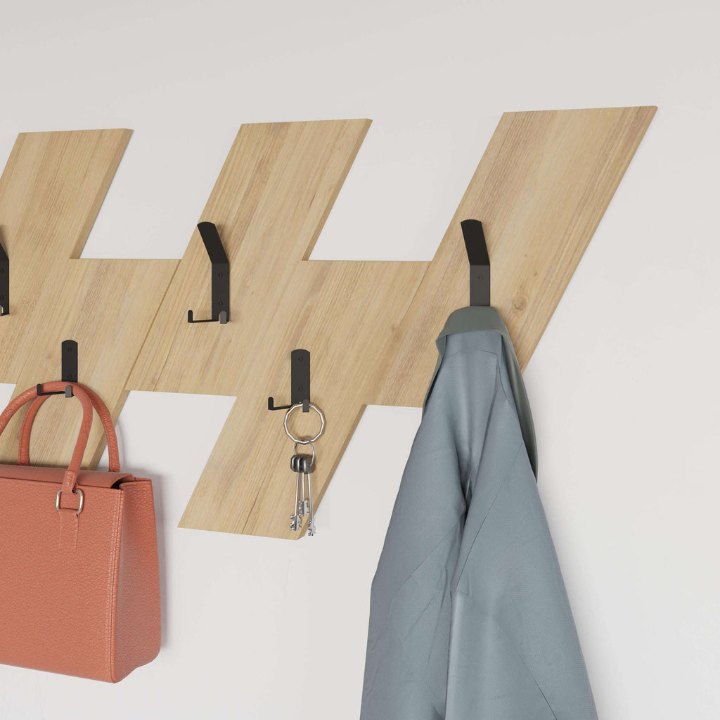 Wall-mounted coat hanger with light wood backboard and black peg hooks for coats
