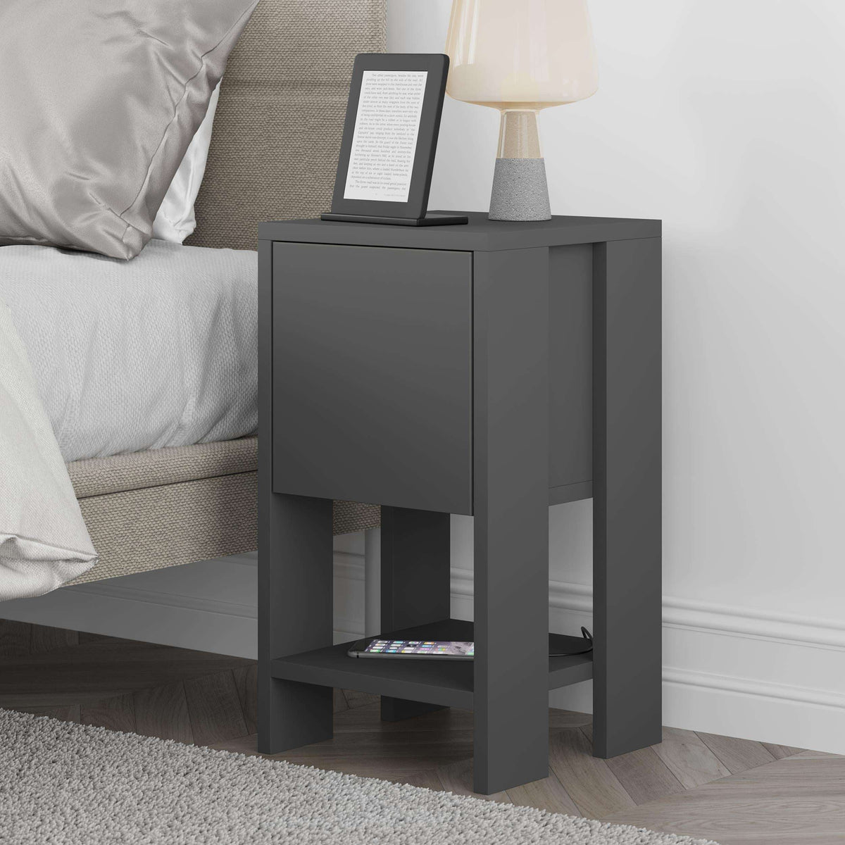 Modern bedside table in dark gray with closed drawer front and open lower shelf