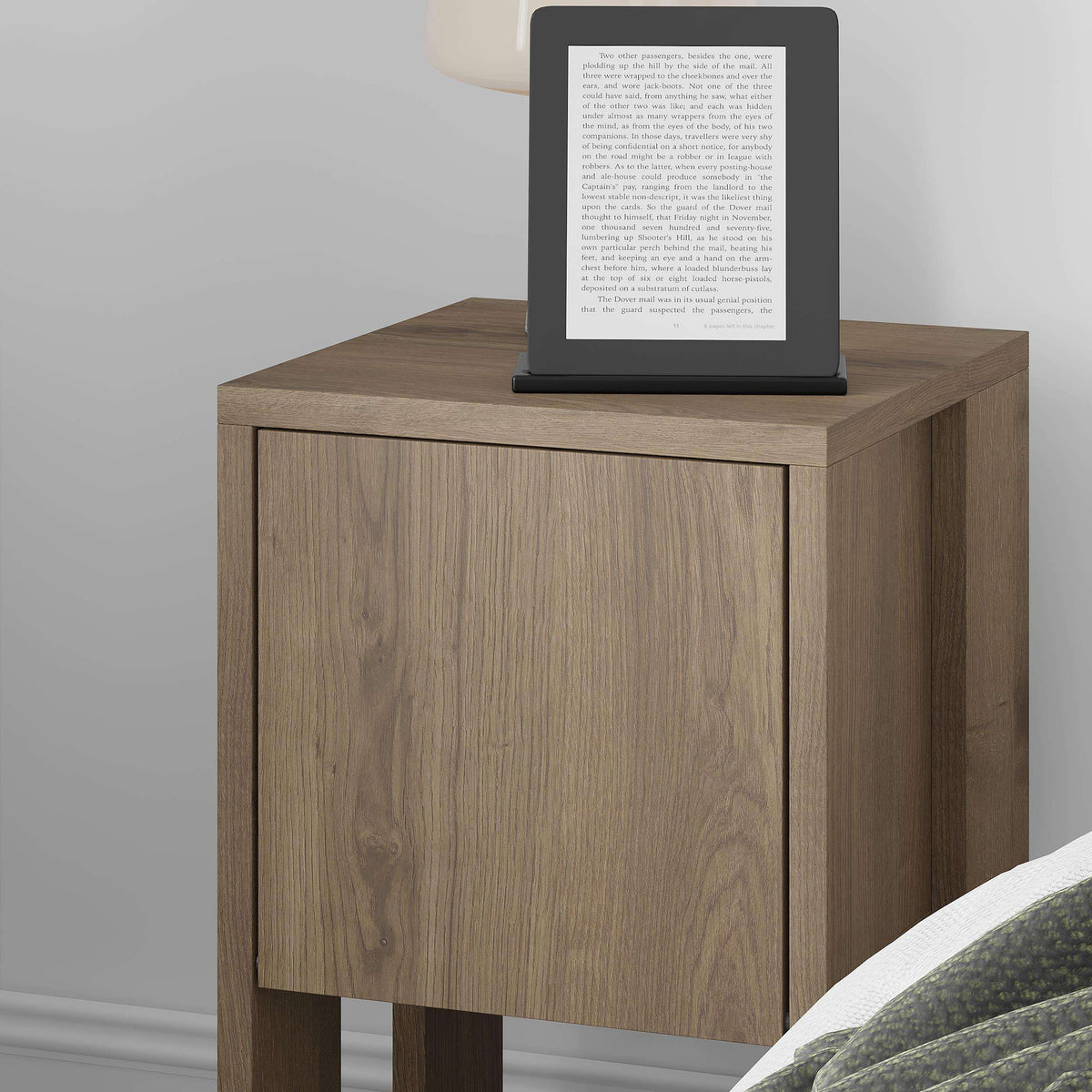 Woodgrain bedside table with single door and open shelf, holding a tablet stand.