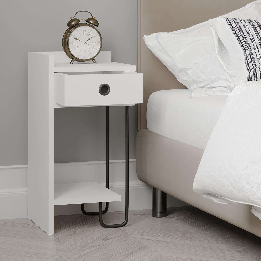 White bedside table module beside bed with drawer, open shelf, and black legs