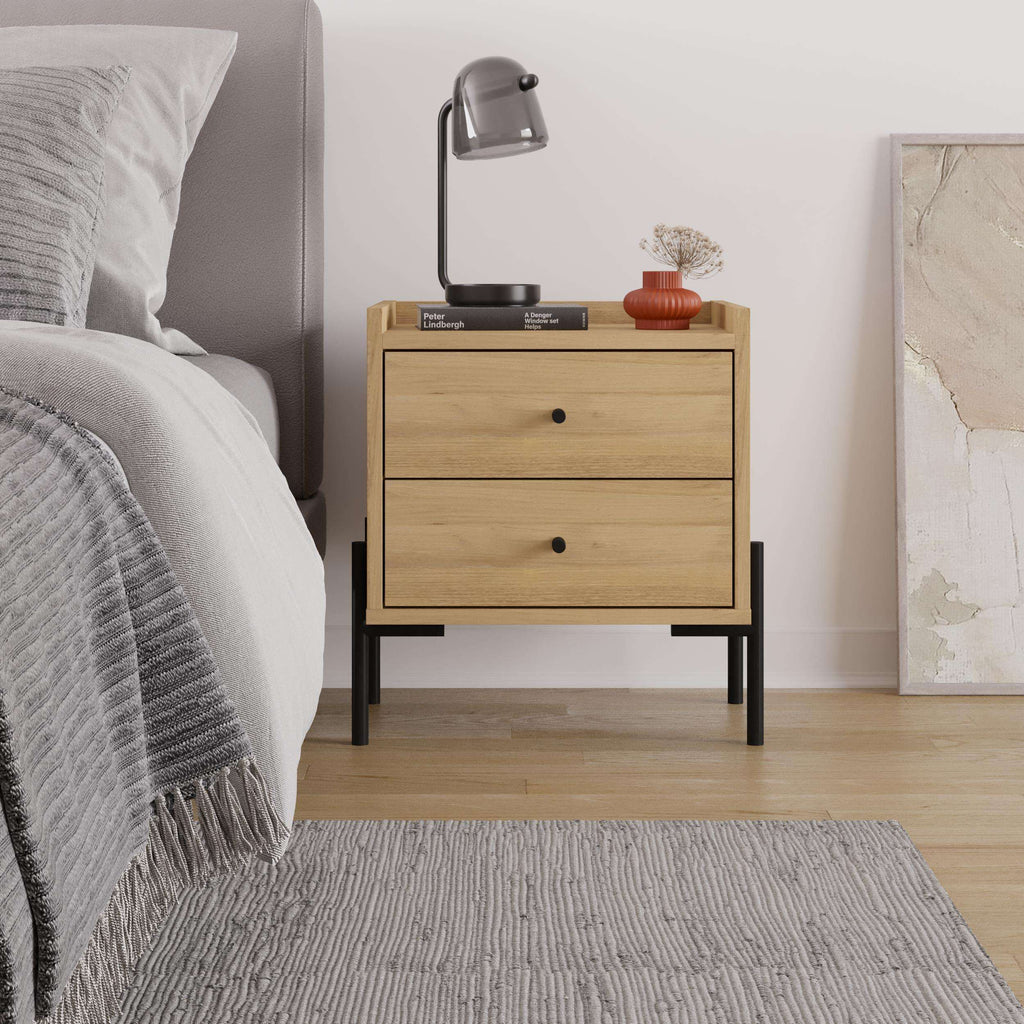 Bedside table with 2 drawers, light oak finish, black legs beside bed and rug