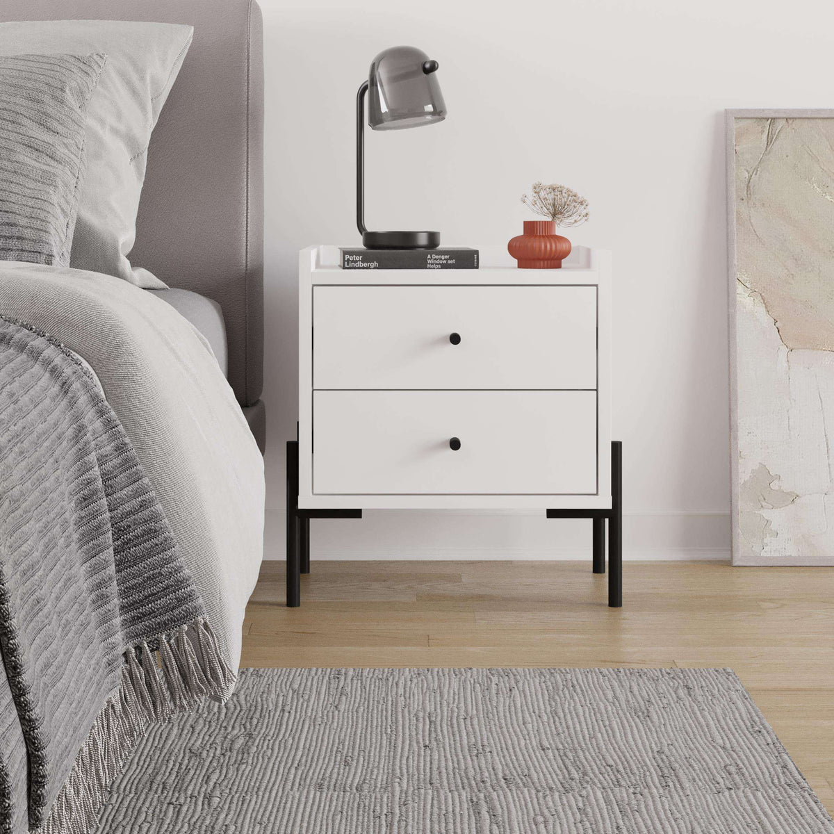 White bedside table with two drawers, black legs, and centered black drawer knobs