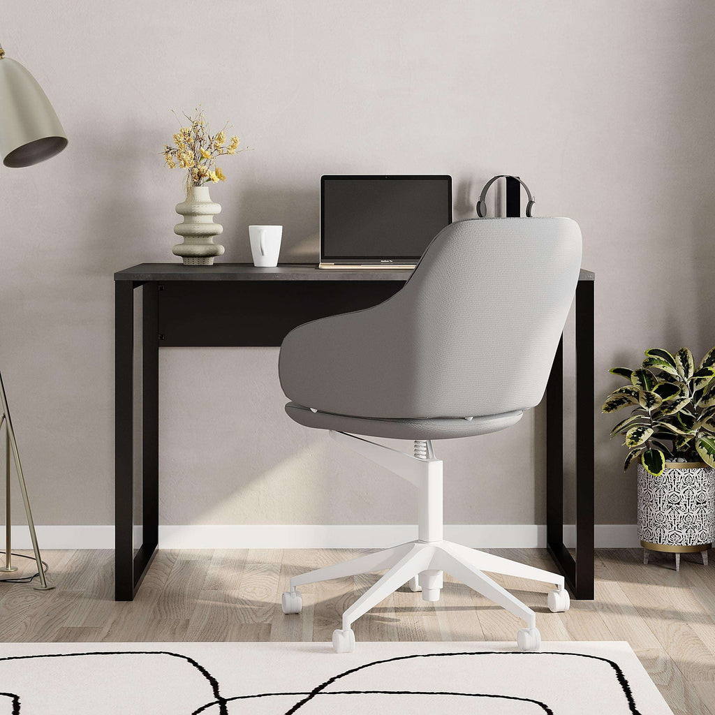 Dark working table with black frame, corner view next to a swivel chair