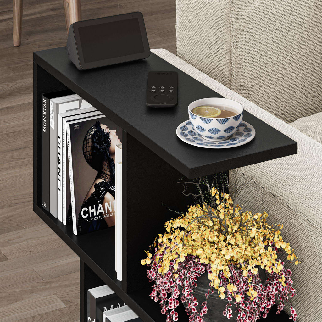 Side table with four open shelves in black, with remote, cup, and book displays