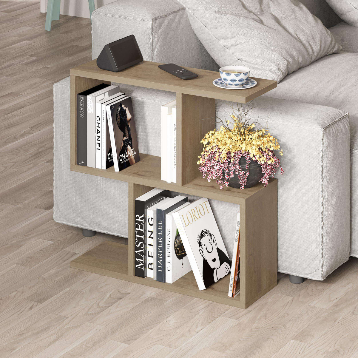 Side table with four open shelves in light wood, topped with remote and cup