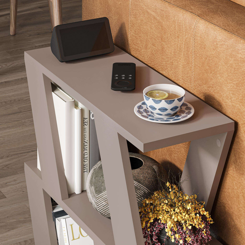 White compact side table with open shelves and tabletop cup, beside brown sofa