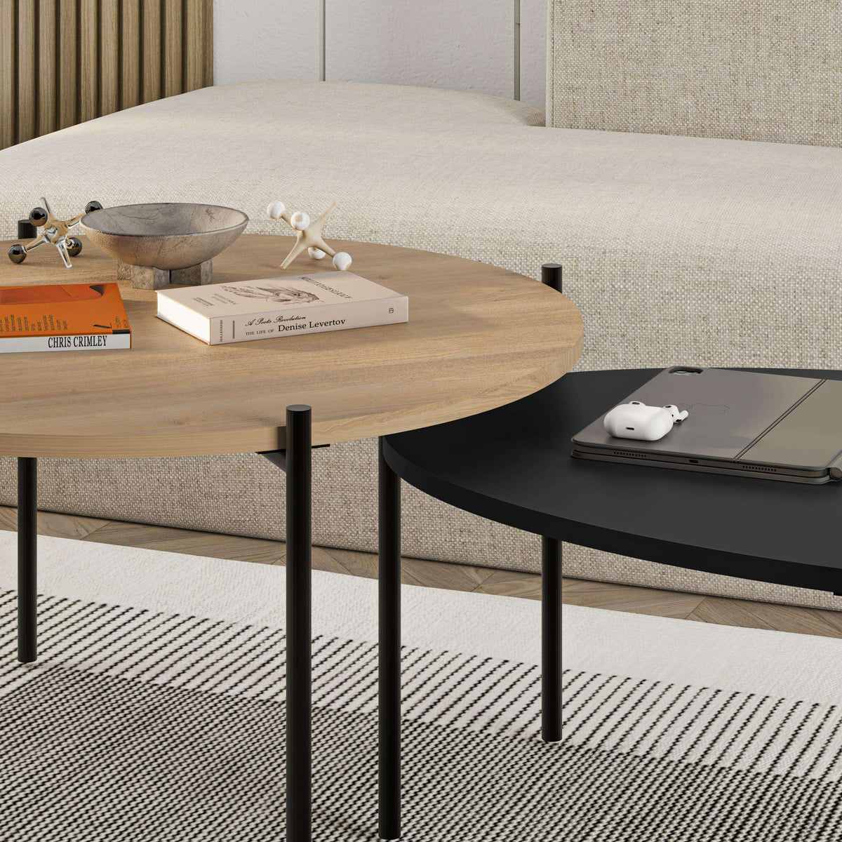 Nested coffee table set with light wood round top and dark oval top on black legs.