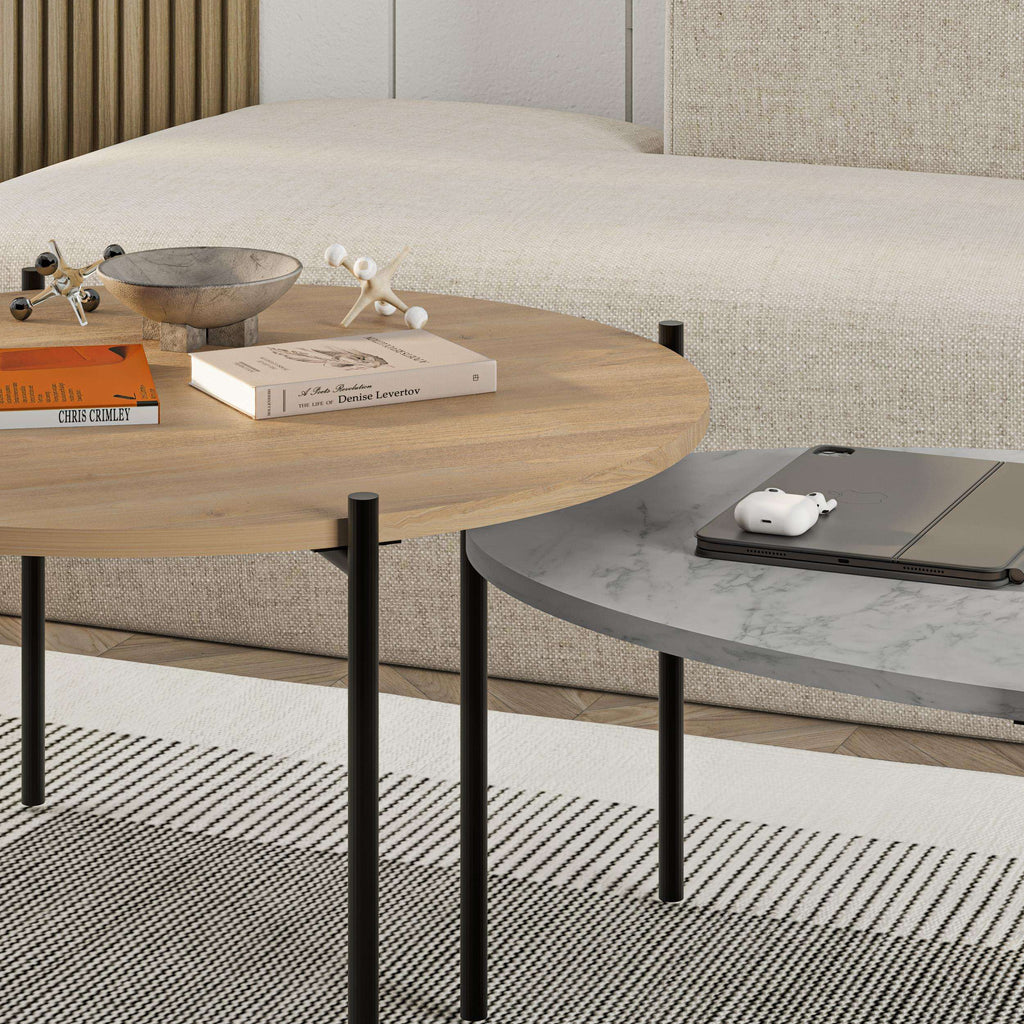 Nested coffee table set featuring a light wood round table and a dark oval table with legs.