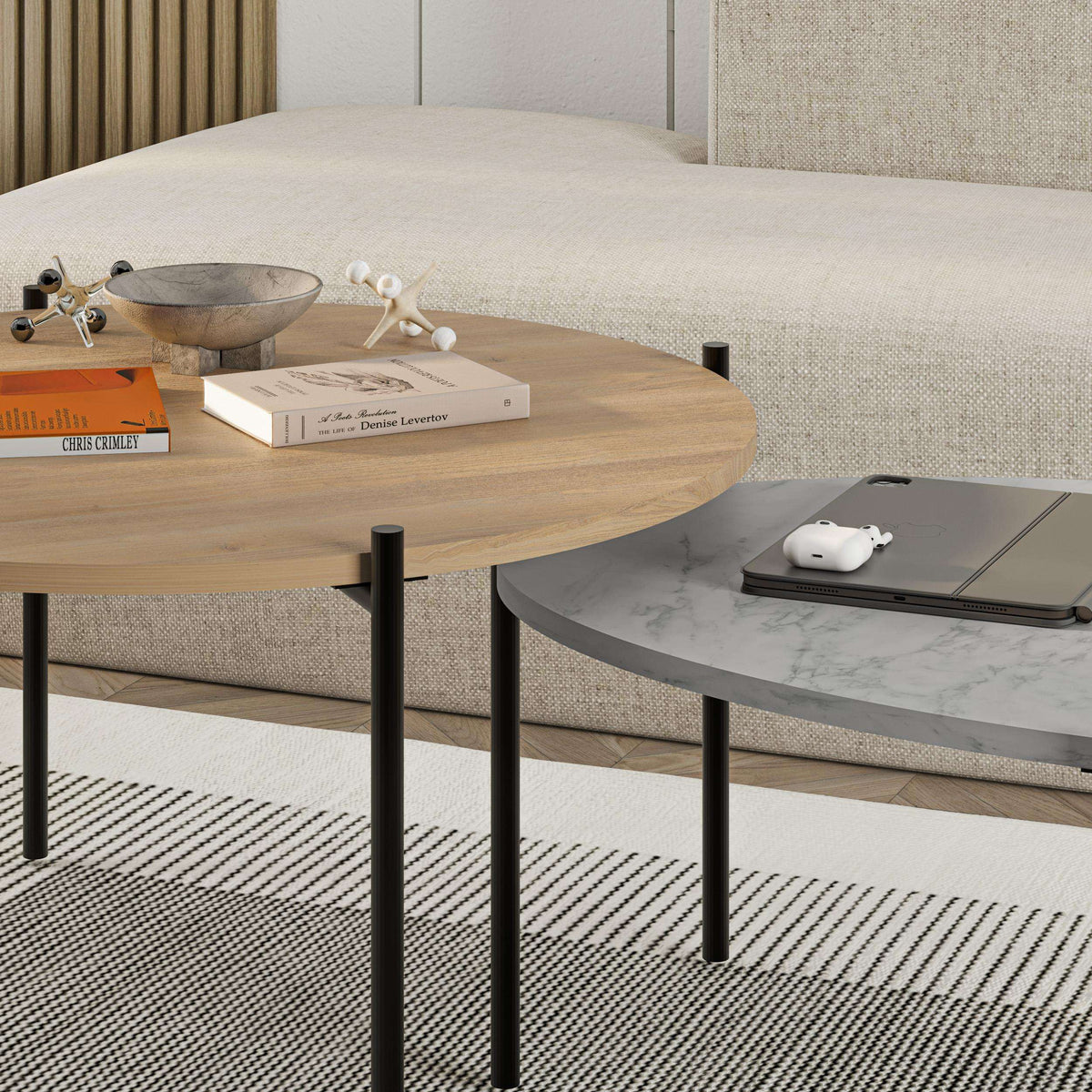 Nested coffee table set featuring a light wood round table and a dark oval table with legs.