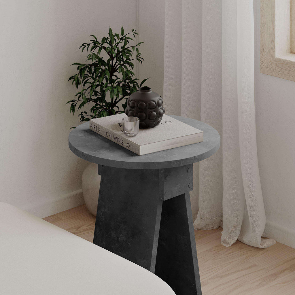 Dark grey round side table with stone-look top and angled pedestal legs