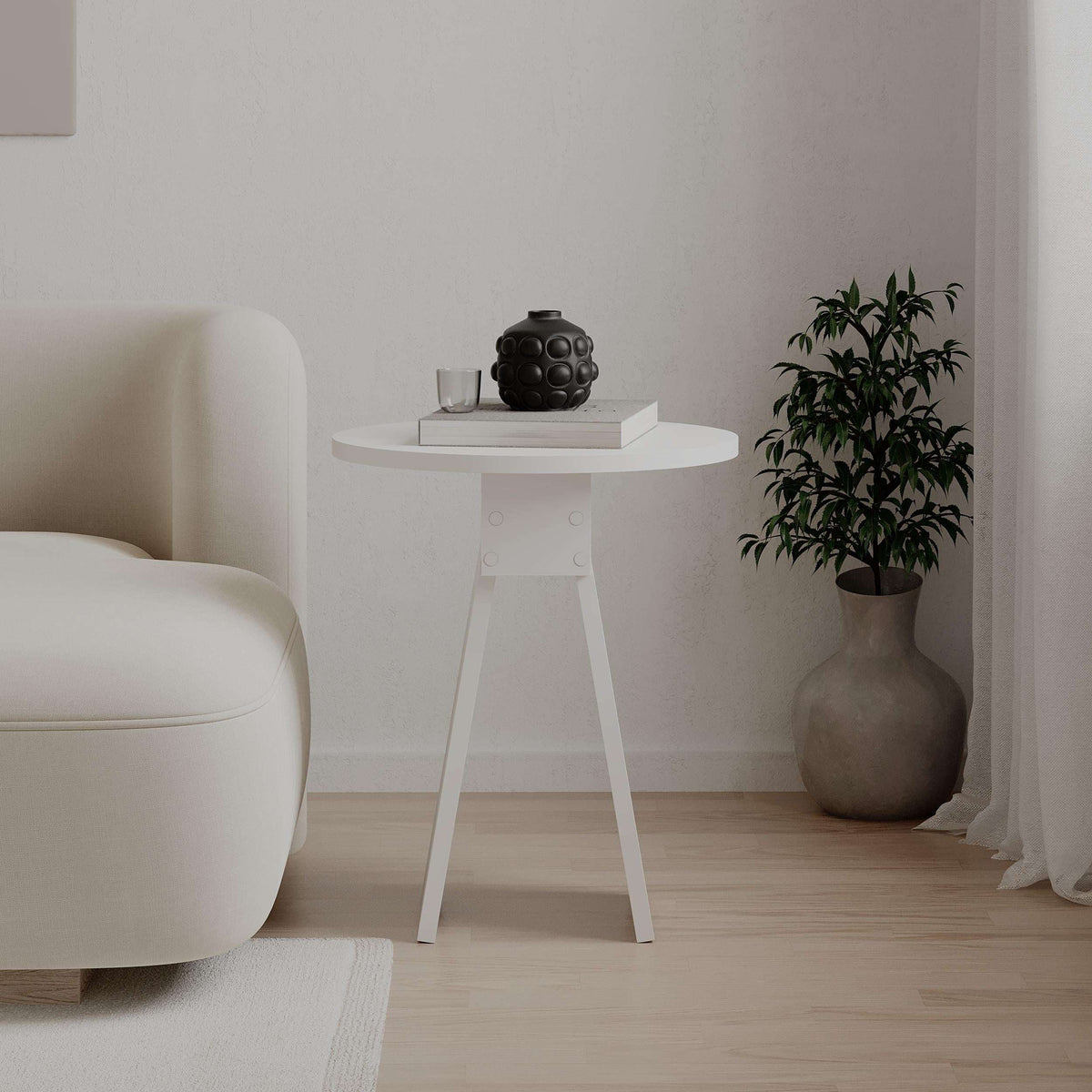 White round side table with pedestal legs, styled with decor items