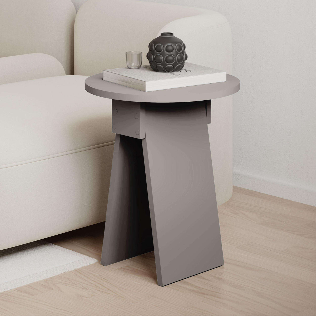 Round side table with grey tabletop and light legs, styled with decor