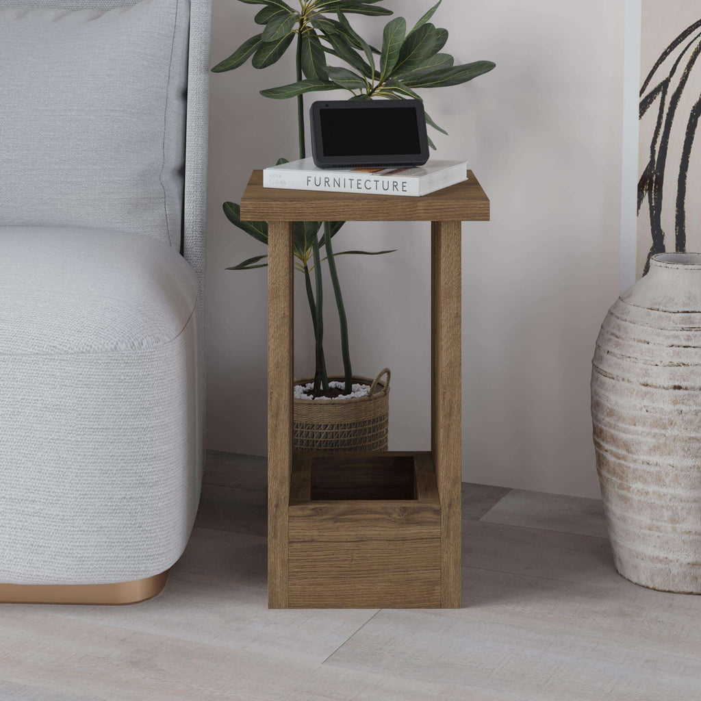 Light wood side table with open center shelf and top surface, shown beside a sofa
