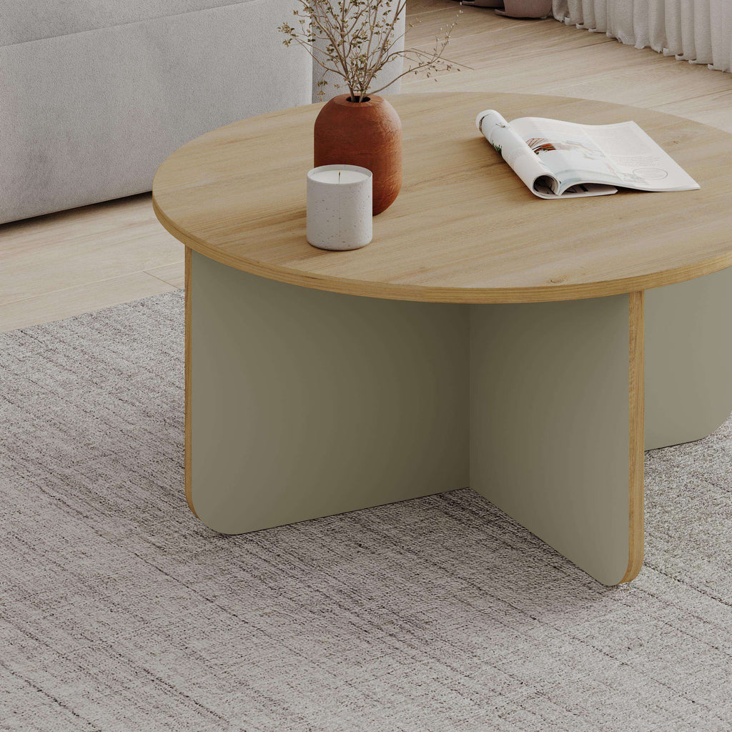 Round coffee table with light wood top and light green curved base, angled view.