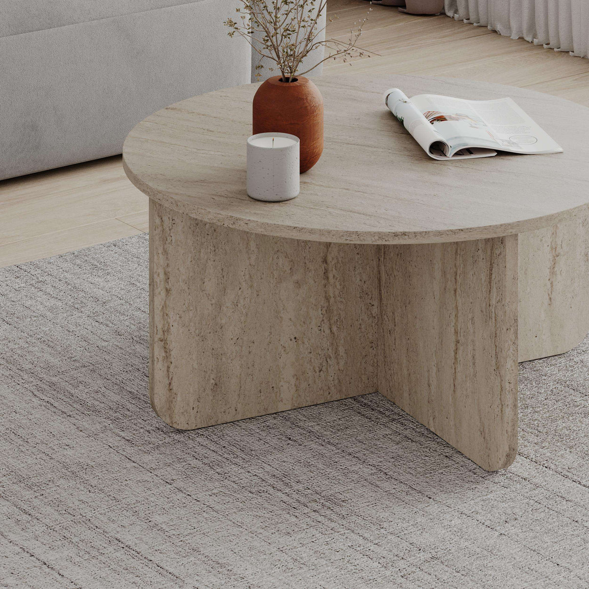 Round coffee table with travertine-look top and curved pedestal base