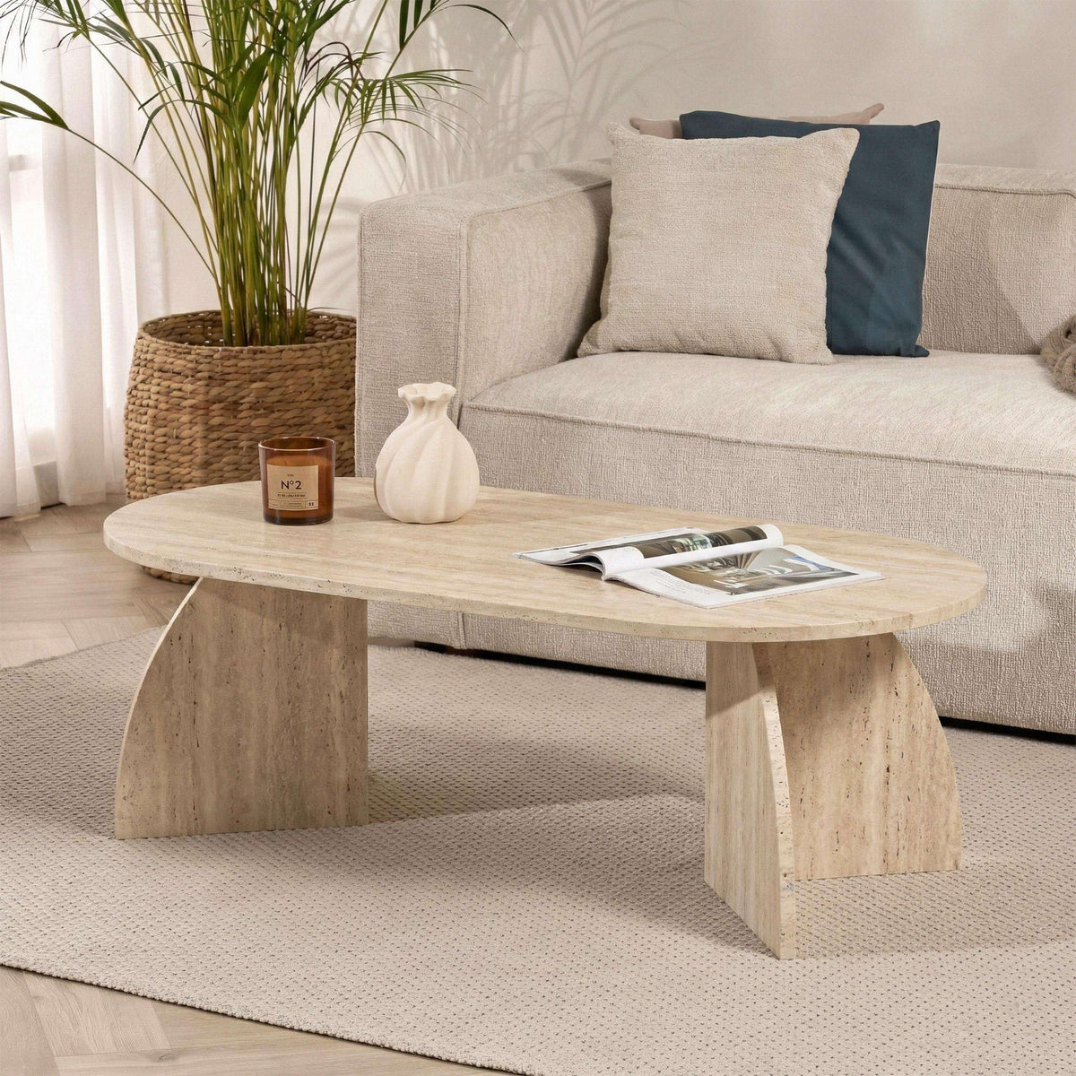 Oval coffee table with light travertine-look top and thick angled legs