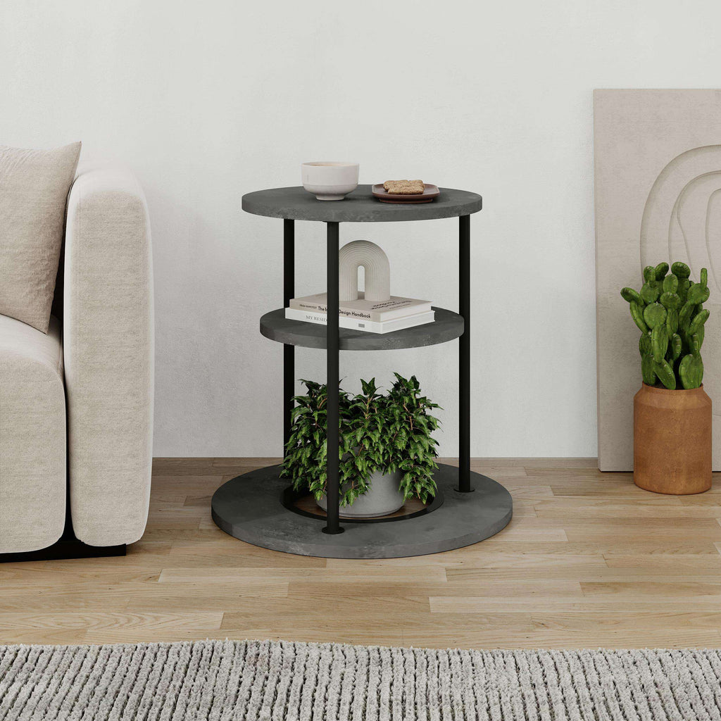 Round side table with two shelves, dark metal frame, textured grey top and small decor.